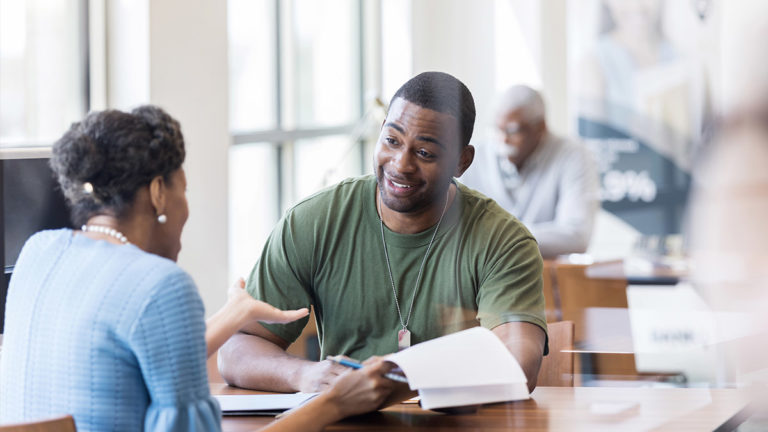 Military veteran and a credit union employee discussing a credit loan