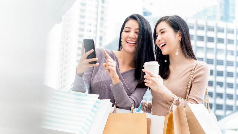 Two women shopping and drinking coffee representing Temenos retail banking