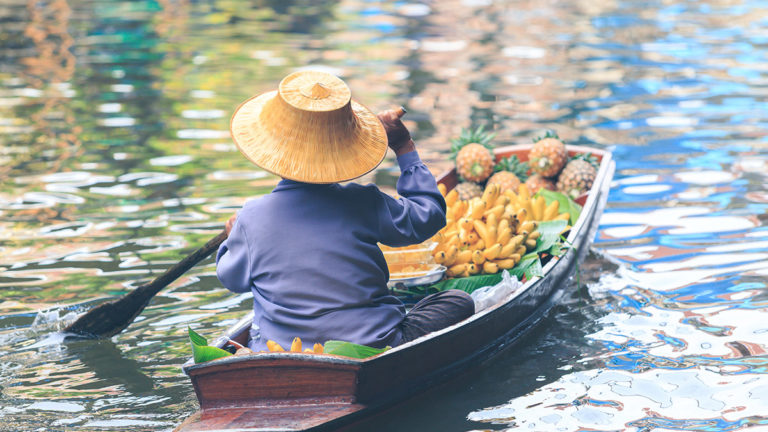Woman in boat sells food at Thai floating Market. Bangkok.