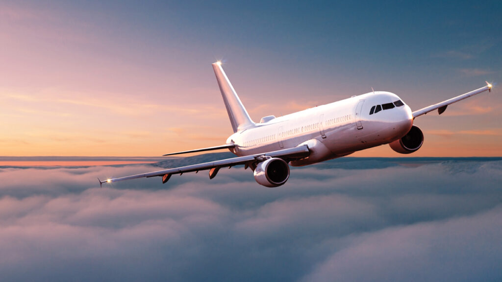 Plane flying above clouds at sunset