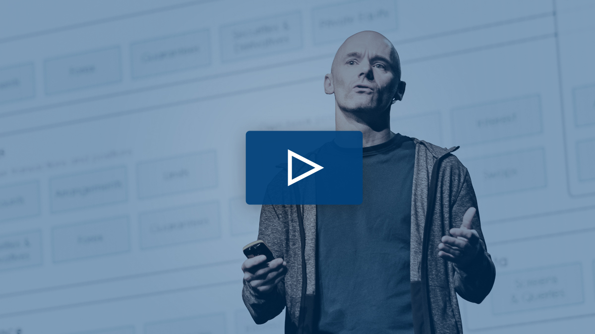 Image of a man talking to a audience with a play sign illuminated 