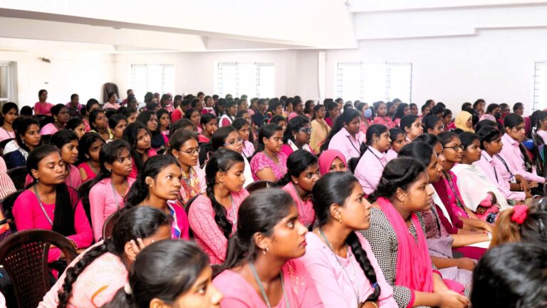 International Women's Day group photo with women all dressed in pink sitting in a room