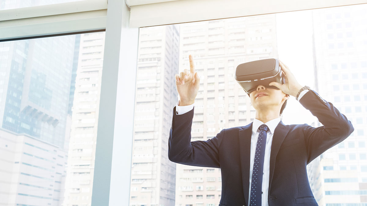 A man in a suit uses a VR headset, standing by large windows with a cityscape view. He points upward, conveying curiosity and innovation.
