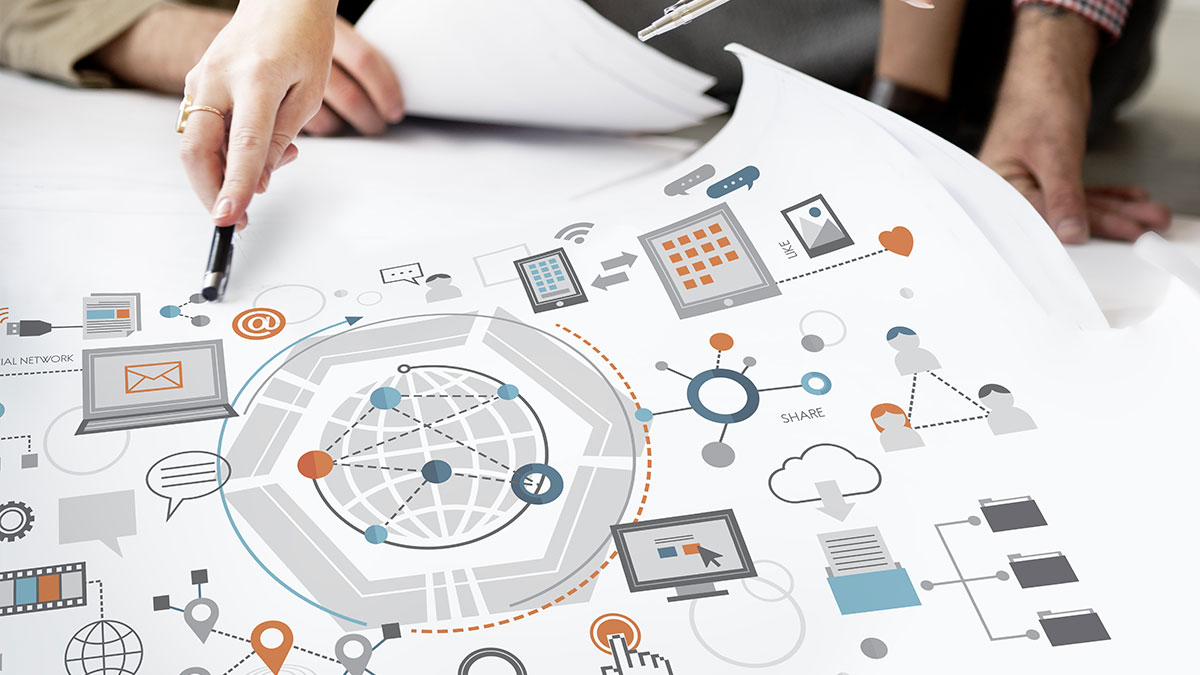 A hand points a pen at a digital network infographic with icons of computers, charts, and communication symbols, conveying collaboration and data sharing.
