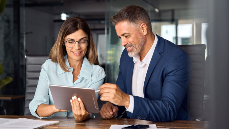 Female and Male business associates looking at a tablet screen and smiling