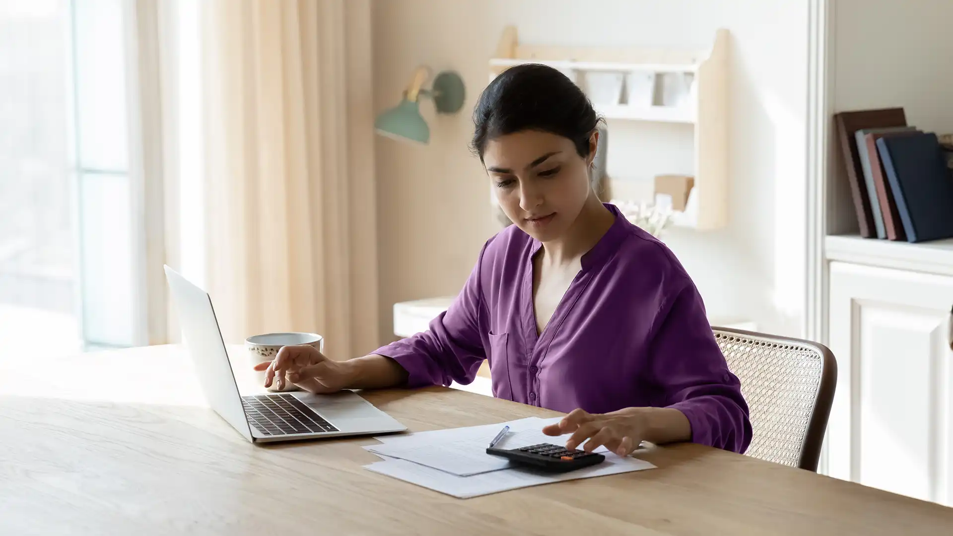 woman sitting at desk with computer and calculator