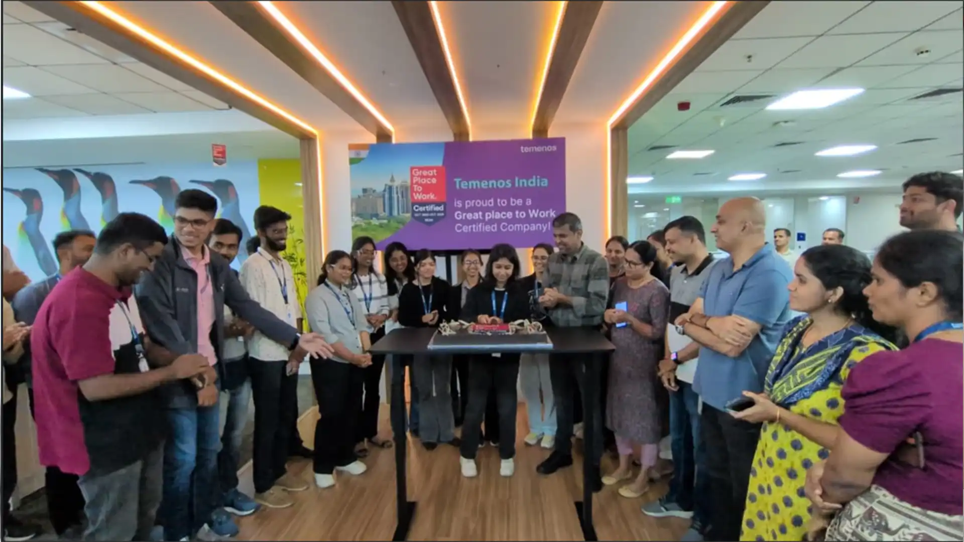 Employees in India office, standing in front of a Great place to Work sign celebrating