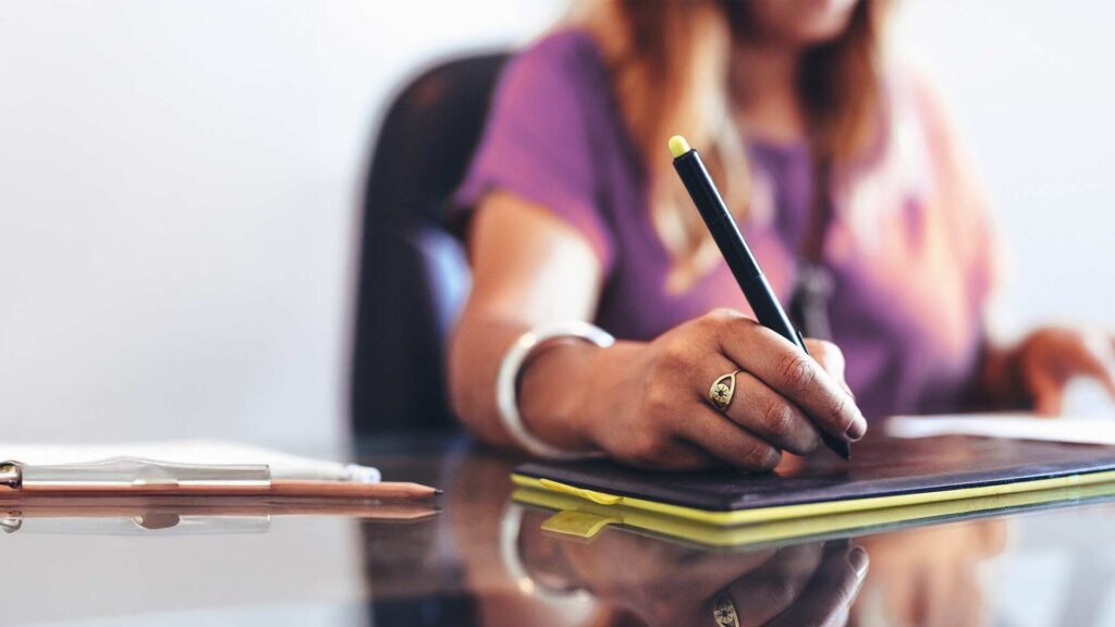 Woman writing on clipboard at desk